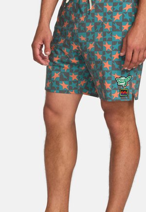 Badeshorts in Türkis mit orangefarbenem Sternmuster, strukturiertem Stoff, verstellbarem Bund und mehreren bunten Patches am Bein.