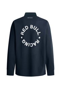 Modra polo majica z dolgimi rokavi in ovratnikom, na hrbtni strani ima velik bel krožni logotip, na katerem je napis "RED BULL RACING."