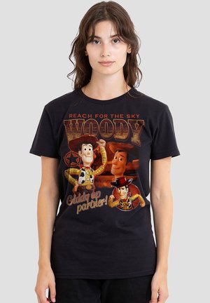 Woman wearing black T-shirt featuring three Woody characters from Toy Story and text "Reach for the sky Woody" and "Giddy up partner!"