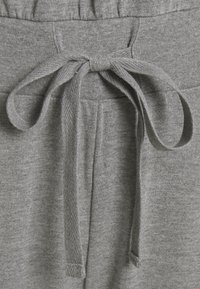 Grå bomulds sweatpants har en elastisk talje med en knyttet snor. Stoffet har en blød tekstur og en meleret finish.