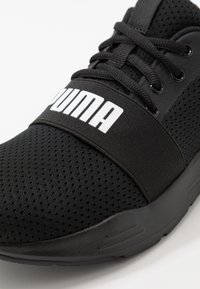 Zwarte sneaker van mesh-stof en vaste accenten, met een brede elastische band met het "PUMA"-logo, vetersluiting en een gestructureerde zool.