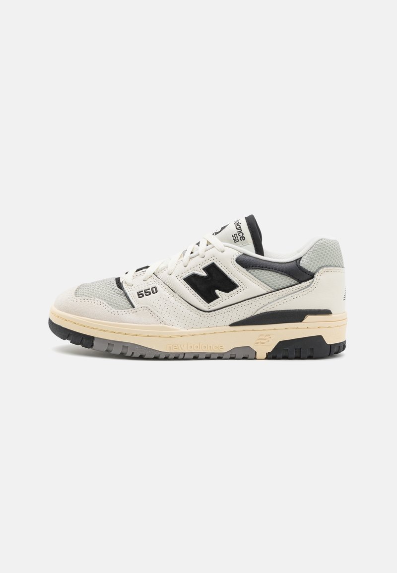 Baskets New Balance 550 blanches et grises avec des accents noirs, « 550 » sur le côté, « new balance » sur la semelle et des panneaux en cuir perforé.