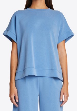 Light blue oversized t-shirt made of a soft fabric, featuring a round neck, short sleeves, and a relaxed fit with a layered hem.