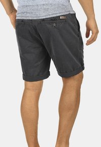 Shorts gris foncé en tissu léger, avec un ourlet replié, des poches latérales et une étiquette en cuir. Conçus avec une coupe décontractée.