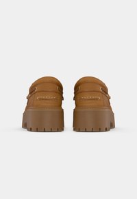 Brune skinn plattform loafers med dekorative sømmer og gull-øyer, med en kraftig såle med dype spor for godt grep.
