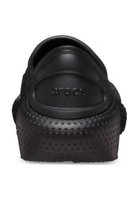 Czarne gumowe klapki z teksturowaną powierzchnią i wypukłymi kropkami, z tylnym paskiem na piętę oraz zaokrąglonym noskiem z logo "crocs" z boku.