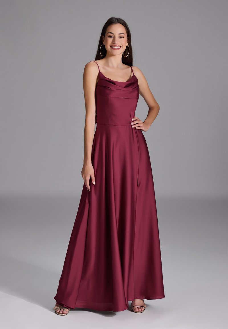 Robe de soirée en satin bourgogne avec un décolleté cowl, des bretelles spaghetti, et une jupe fluide, dotée d'une fente sur le côté et d'un ourlet au niveau des chevilles.