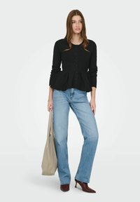 Sort peplum-cardigan med rund hals og knaplukning, kombineret med lyseblå jeans med lige ben og vinrøde spidse hæle.