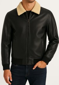 Schwarze Lederjacke mit einem cremefarbenen Schafslederkragen, Reißverschluss vorne, gerippten Manschetten und Saum sowie Seitentaschen. Glatte Textur, klassischer Bomberstil.