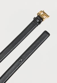 Μαύρη δερμάτινη ζώνη με αγκράφα από μέταλλο σε χρυσή απόχρωση. Μάλλινη υφή, διαθέτει πολλαπλές τρύπες ρύθμισης και κομψό, μινιμαλιστικό σχέδιο.