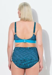 Teal bikini ylin osa ja korkeavyötäröiset alaosat, joissa on kalakuosi. Varustettu säädettävillä olkaimilla, hakasella ja sileällä, teksturoidulla kankaalla.