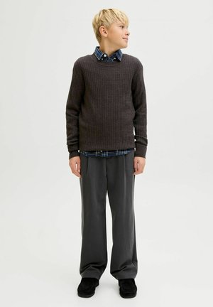 Dunkelgrauer gerippter Pullover über einem blau karierten Hemd, kombiniert mit lockeren dunkelgrauen Hosen und schwarzen Schuhen. Einfaches und texturiertes Design.