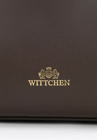 Brązowa skórzana torba o fakturze z złotym logo "WITTCHEN" z dekoracyjnym emblematem powyżej. Powierzchnia jest gładka o matowym wykończeniu.