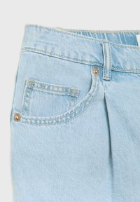 Jean en denim bleu clair montrant une poche avant, une boucle de ceinture et des rivets métalliques avec des détails de couture contrastés.