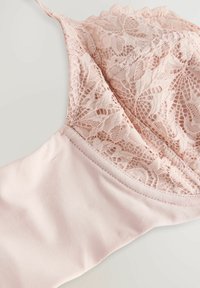  Lichtroze beha met bloemenkant en gegolfde randen, gemaakt van gladde stof. Rondom gevormde cups en verstelbare bandjes voor een comfortabele pasvorm.