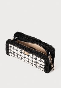 Borsa a mano con bordo in pelliccia sintetica nera, motivo a zig zag bianco e nero, zip dorata e tracolla a catena. L'interno è foderato ed è color camoscio.