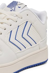 Białe trampki z niebieskimi akcentami i wzorem w zygzaki, wykonane ze skóry z perforowanymi detalami, z jasną podeszwą i sznurowadłami.