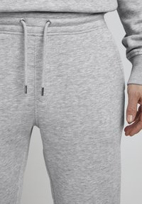 Grijze sweatpants met een zachte textuur, voorzien van een tailleband met trekkoord en zilveren metalen accenten, en zijzakken voor functionaliteit.