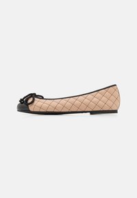 Ballerines en cuir matelassé beige clair avec un embout en vernis noir et un détail de nœud. Profil slim avec une finition mate et des coutures subtiles.