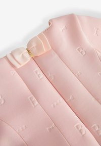 Hellrosa Kleid mit geprägten "B"- und Schleifenmustern, ausgestattet mit einer Satinband-Schleife und einem Reißverschluss auf der Rückseite. Glatte Textur.