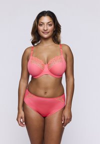 Reggiseno corallo con dettagli in pizzo lungo la parte superiore e slip a vita alta abbinato. Texture liscia, supporto con stecche, spalline regolabili.