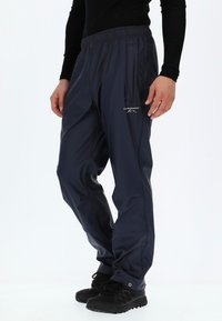 Navy wasserdichte Hose mit elastischem Bund, Seitentasche und Logodetail. Hergestellt aus einem glatten, leichten Material. Geeignet für den Außeneinsatz.