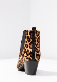 Leopardikuvioiset nilkkurit, jotka on valmistettu teksturoidusta turkiksesta ja mustista elastisista paneeleista. Niissä on pino korko ja takaosassa vetoluukku.