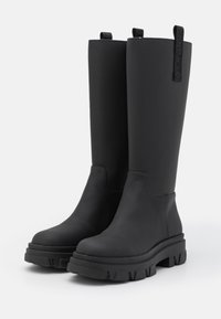 Zwarte rubberen laarzen tot aan de knie met een gladde textuur, grove profielzool en trekbandjes voor gemakkelijk aan- en uittrekken. Eenvoudig ontwerp zonder extra accenten.