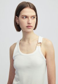 Witte geribde tanktop met een ronde hals en verstelbare bandjes, voorzien van een gouden hardware accent. Zacht katoen materiaal.