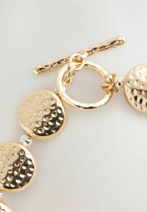 Gold-tone bracelet featuring round, hammered discs and polished accents, secured with a toggle clasp. Smooth and textured surfaces.