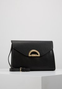 Borsa a tracolla in pelle nera texturizzata con chiusura a patta angolata, fibbia circolare dorata e tracolla removibile.