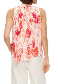 Ärmellose Bluse mit floralem Muster in Rottönen und Rosa, ausgestattet mit einem plissierten Design und einer Bindeschließe im Rücken.
