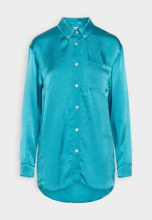 Τυρκουάζ μακρυμάνικη μπλούζα με υφή, κουμπωτή μπροστινή πλευρά και μία τσέπη στο στήθος. Στρογγυλεμμένο τελείωμα και γιακά.