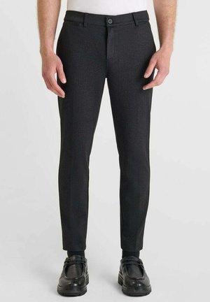 Zwarte gepersonaliseerde broek van een textuurstof, slim-fit ontwerp en een enkele knoopsluiting. Gecombineerd met zwarte schoenen.