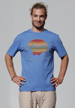 Blaue Baumwoll-T-Shirt mit einem runden Grafikdesign, das horizontale Streifen in Orange, Gelb und Rot zeigt, die Berge und Vögel darstellen.