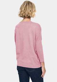 Helles rosa, geripptes Sweatshirt mit lockerer Passform, 3/4-Ärmeln und rundem Halsausschnitt. Glatte Textur mit einer Naht entlang des Rückens.