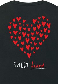 Červená srdce vytvářejí velký tvar srdce na černém pozadí, s nápisem "SWEET heart" v bílé a červené barvě pod designem.