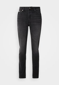 Schwarze Jeans aus Denim mit schmaler Passform, fünf Taschen und Knopfverschluss. Mit einem subtilen Verblassen und Nähakzenten an den Taschen.