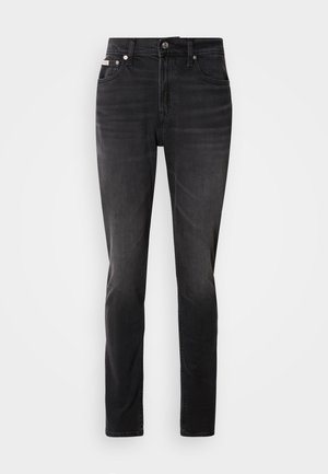 Jean en denim noir avec une coupe ajustée, design à cinq poches et fermeture par bouton. Présente un dégradé subtil et des accents de couture sur les poches.