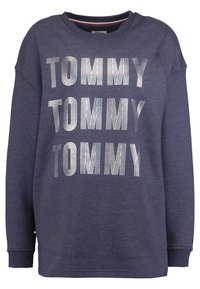 Námořnický modrý svetr s velkým texturovaným nápisem "TOMMY" v alternativních pruzích. Vyrobeno z měkké látky s žebrovanými manžetami a výstřihem.