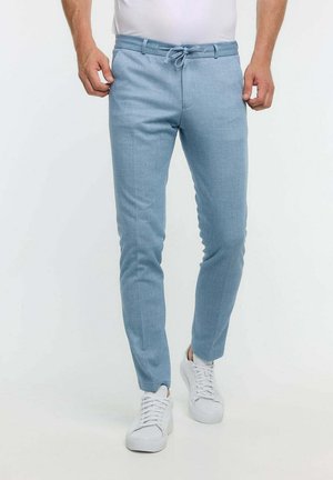 Light blue tailored trousers made of soft fabric, featuring a drawstring waist, slim fit, and front pockets. Worn with white sneakers.