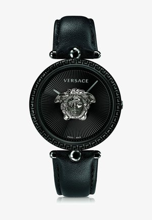 Schwarze Lederarmbanduhr mit einem runden schwarzen Zifferblatt, silbernem Medusenemblem, strukturiertem Hintergrund und griechischem Schlüsseldesign auf der Lünette.