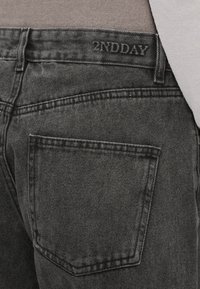 Črne jeans hlače iz jeansa z teksturirano površino, z zadnjim žepom in logotipom "2NDDAY" izvezanim na pasu.