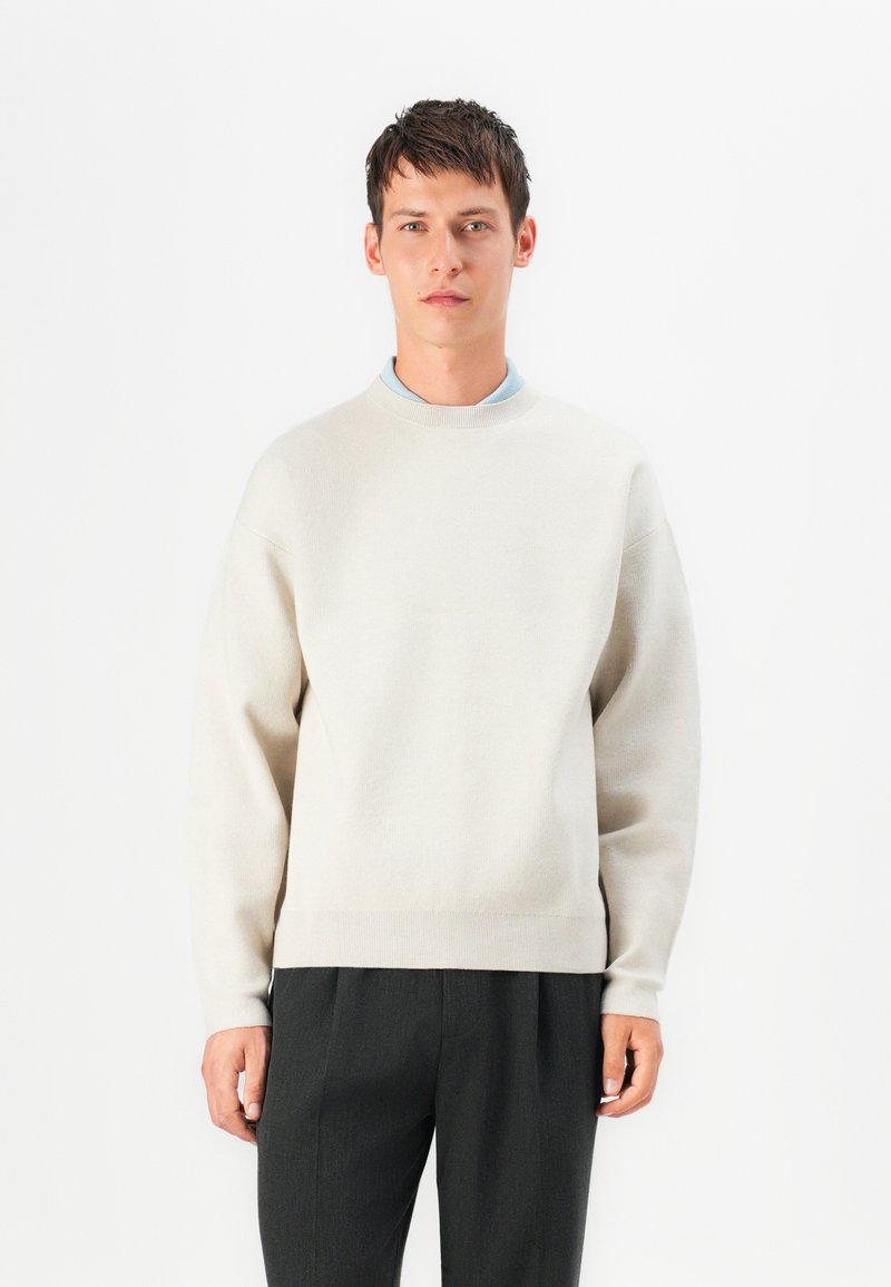 Sweatshirt de gola redonda em cinza claro, com mangas longas, feito de um tecido macio. Apresenta um corte relaxado e um design simples, sem adornos.