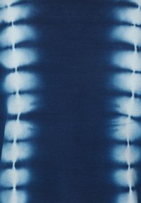 Blå tyg med ett symmetriskt tie-dye-mönster som har vertikala vita streck längs båda kanterna.