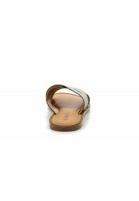 Flat sandals with a brown sole, silver strap design, and a smooth, slightly textured insole. Open toe and backless style.