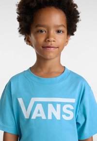 Tyrkysové bavlněné tričko s velkým bílým logem "VANS". Krátké rukávy a kulatý výstřih s hladkým povrchem.