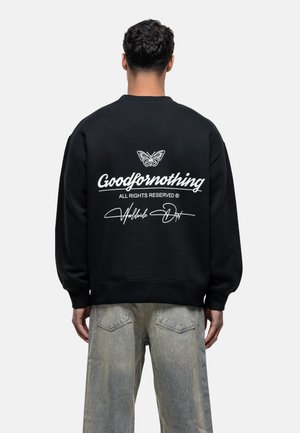 Black sweatshirt with ribbed cuffs and hem, featuring a white butterfly graphic and "Goodfornothing" text on the back. Smooth cotton blend fabric.