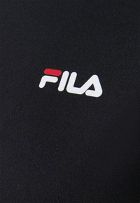 Tessuto nero con logo "FILA" in rilievo bianco, con accenti rossi e blu. Texture liscia, design aderente e bordi puliti.