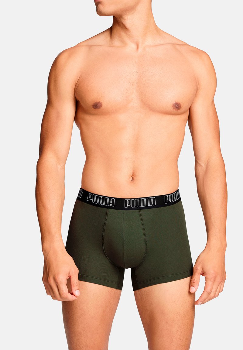 Grüne Boxershorts mit einem schwarzen elastischen Bund, der das Puma-Logo trägt. Das Material sieht glatt aus und hat eine taillierte Form mit kurzen Beinen.